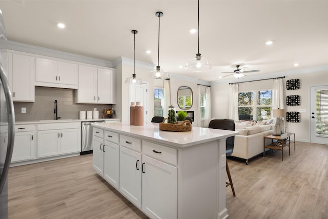 kitchen featuring a center island, dishwasher, white cabinets, hanging light fixtures, and sink