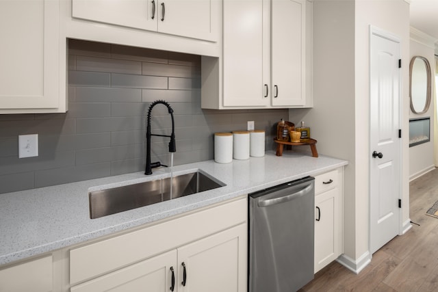 kitchen with dishwasher, sink, tasteful backsplash, light stone countertops, and light wood-type flooring