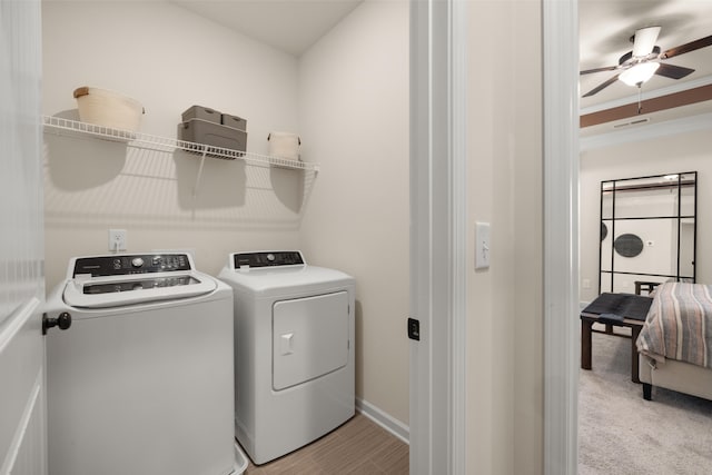 laundry area featuring independent washer and dryer, light colored carpet, and ceiling fan