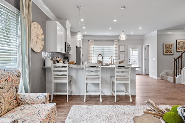 kitchen with white cabinetry, a kitchen breakfast bar, light stone countertops, pendant lighting, and dark hardwood / wood-style flooring