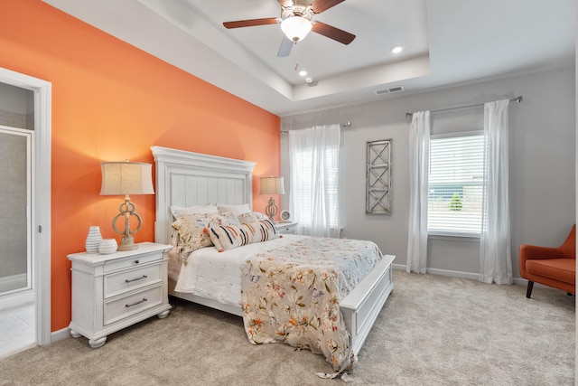 bedroom with ceiling fan, light carpet, and a raised ceiling