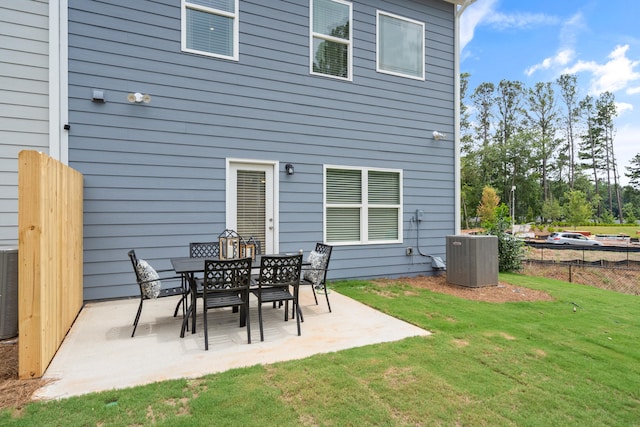 rear view of property with central air condition unit, a lawn, and a patio area