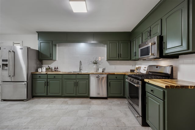 kitchen featuring decorative backsplash, stainless steel appliances, sink, butcher block countertops, and green cabinets