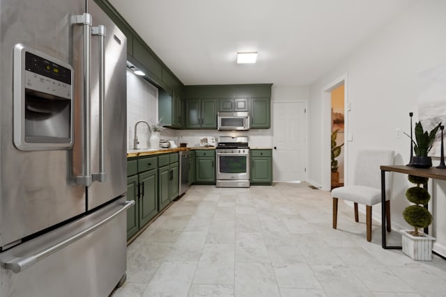 kitchen featuring stainless steel appliances, green cabinetry, and sink