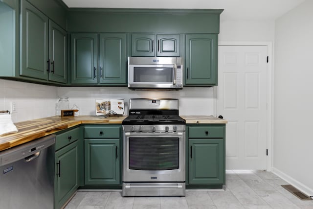 kitchen with wooden counters, decorative backsplash, stainless steel appliances, and green cabinetry