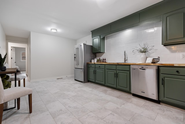 kitchen featuring green cabinets, sink, decorative backsplash, butcher block counters, and stainless steel appliances