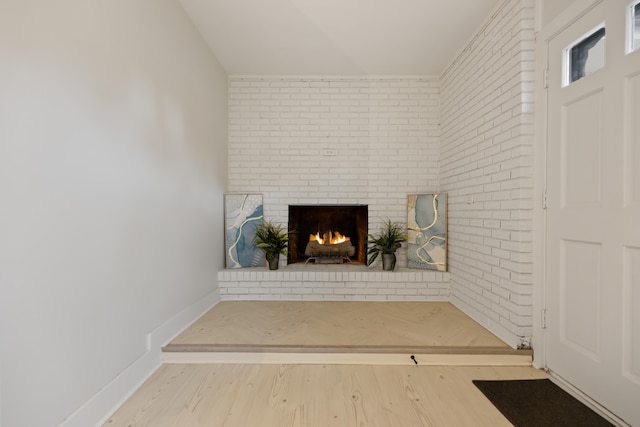 interior space with hardwood / wood-style flooring, brick wall, and a brick fireplace