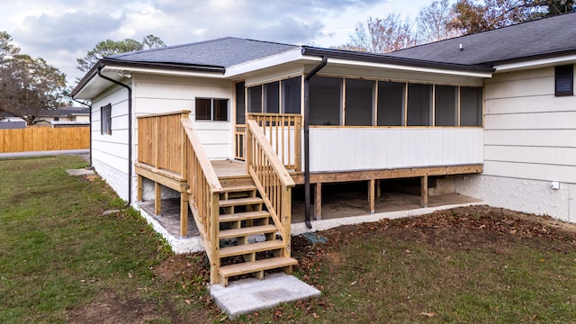 rear view of house featuring a sunroom and a lawn