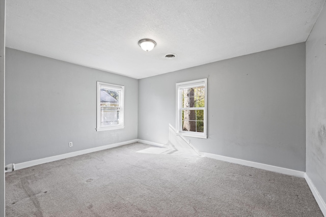 spare room featuring light carpet and a textured ceiling