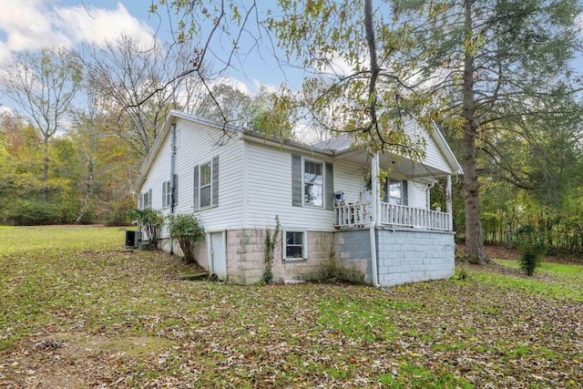 view of side of home featuring central air condition unit, a porch, and a yard