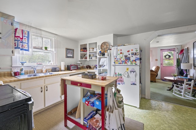 kitchen with white cabinets, plenty of natural light, sink, and white refrigerator