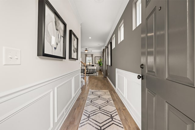 corridor with light wood-type flooring and crown molding