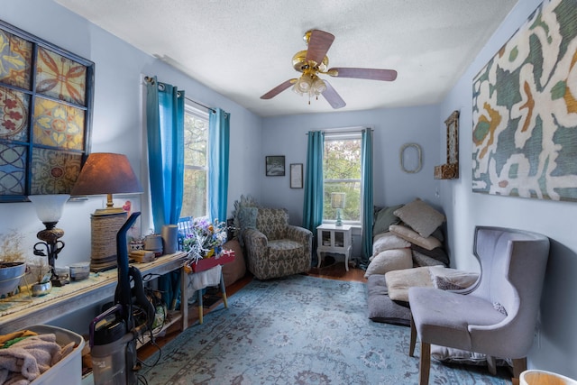 sitting room with a textured ceiling, wood-type flooring, and ceiling fan