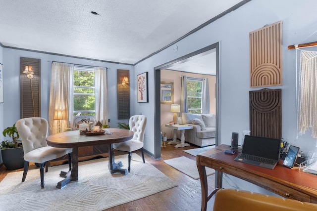 dining space with a textured ceiling, light hardwood / wood-style flooring, ornamental molding, and a healthy amount of sunlight