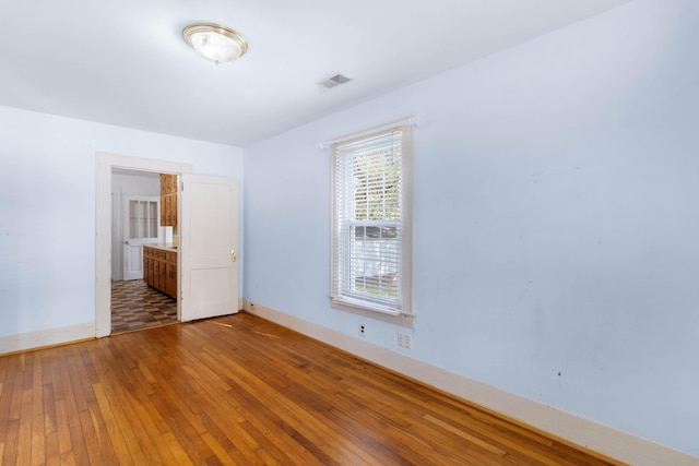 unfurnished bedroom featuring hardwood / wood-style flooring and ensuite bath