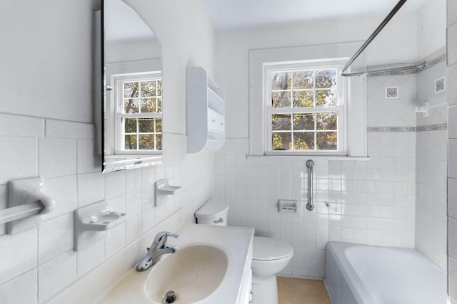 full bathroom with tiled shower / bath, vanity, tile walls, and a healthy amount of sunlight