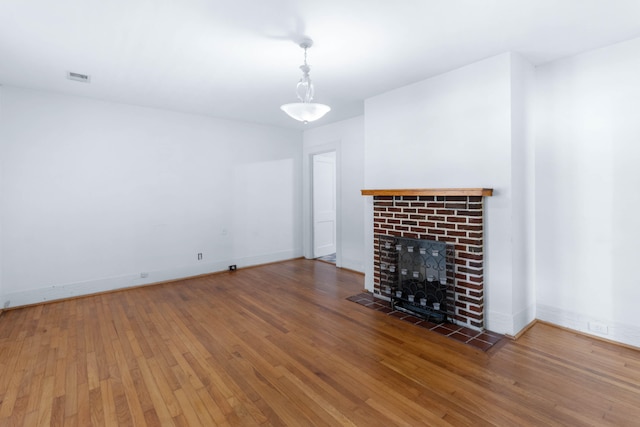 unfurnished living room featuring a brick fireplace and wood-type flooring