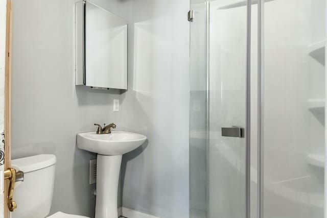 bathroom with toilet, an enclosed shower, and sink