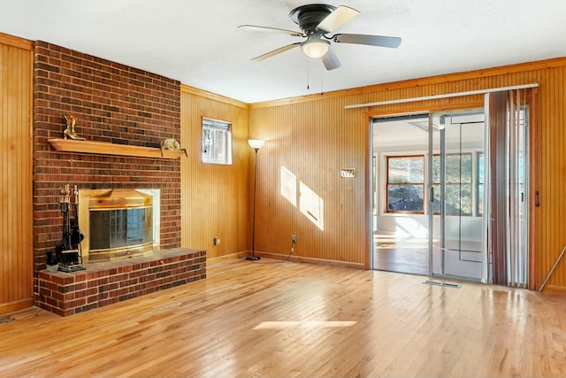 unfurnished living room with hardwood / wood-style flooring, ceiling fan, and wood walls