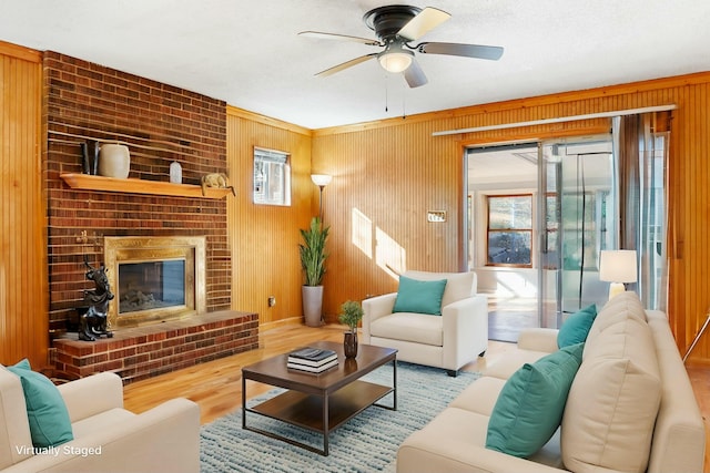 living room with ceiling fan, hardwood / wood-style flooring, and a brick fireplace