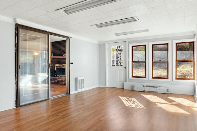 empty room with crown molding, light hardwood / wood-style flooring, and a baseboard heating unit