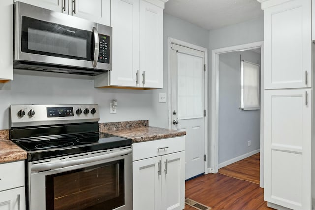 kitchen with white cabinets, stainless steel appliances, and dark hardwood / wood-style floors