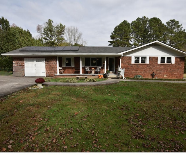 ranch-style home featuring solar panels, a porch, a front lawn, and a garage