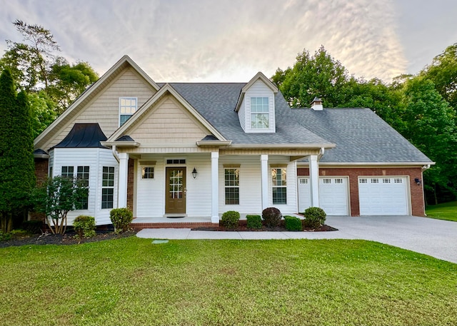 view of front facade featuring covered porch, a front yard, and a garage