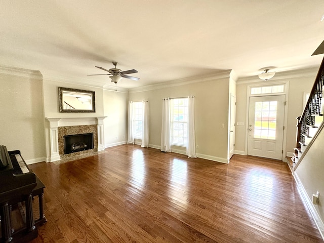 unfurnished living room with dark wood-type flooring, crown molding, ceiling fan, and a healthy amount of sunlight