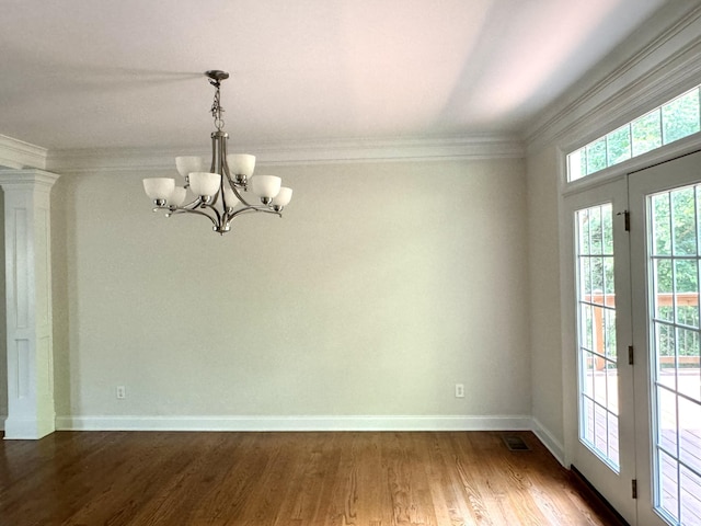 spare room with dark hardwood / wood-style flooring, ornamental molding, and a chandelier