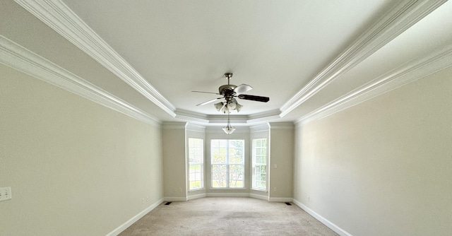 unfurnished room with a tray ceiling, ceiling fan, light colored carpet, and ornamental molding