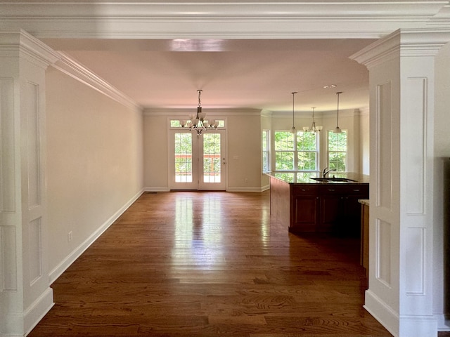 unfurnished dining area with french doors, sink, dark wood-type flooring, a notable chandelier, and ornamental molding