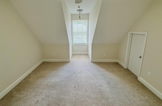 additional living space featuring lofted ceiling and light carpet