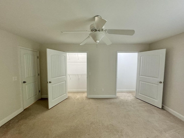 unfurnished bedroom with ceiling fan, light colored carpet, a spacious closet, and a closet