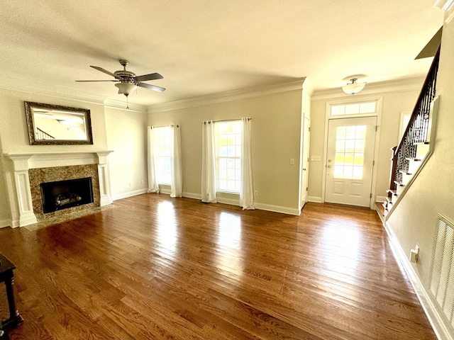 unfurnished living room with ceiling fan, plenty of natural light, hardwood / wood-style floors, and ornamental molding