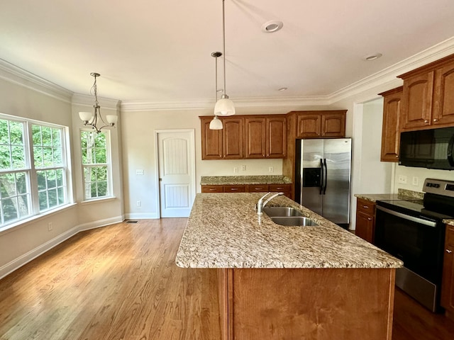 kitchen featuring sink, a chandelier, a center island with sink, appliances with stainless steel finishes, and light wood-type flooring