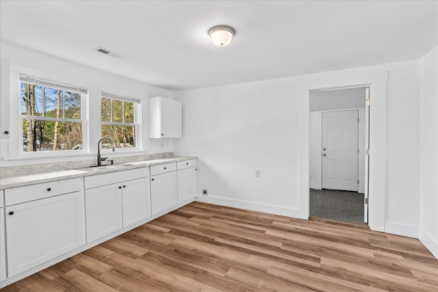 kitchen with light hardwood / wood-style floors, white cabinetry, and sink