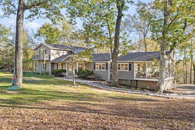 view of front of home featuring a sunroom, a front lawn, and a balcony