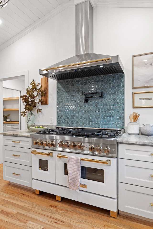 kitchen featuring double oven range, decorative backsplash, ornamental molding, wall chimney range hood, and light wood-type flooring