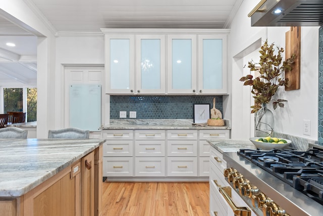 kitchen with light stone counters, crown molding, decorative backsplash, light hardwood / wood-style floors, and white cabinets