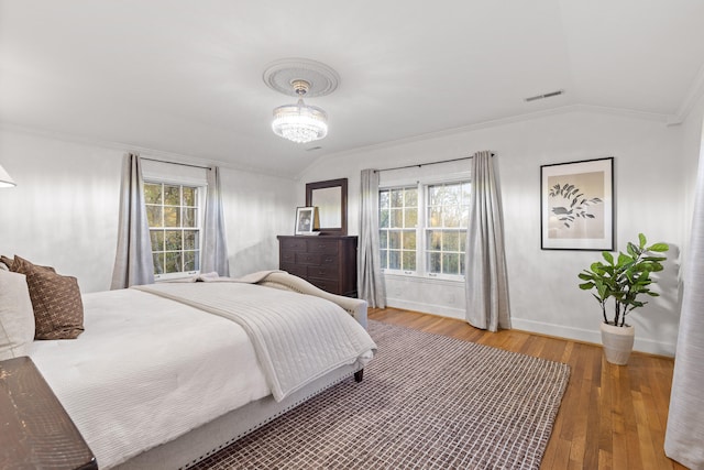 bedroom with ornamental molding, lofted ceiling, multiple windows, and wood-type flooring