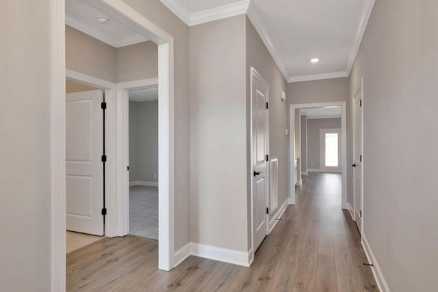 hallway with ornamental molding and light hardwood / wood-style floors