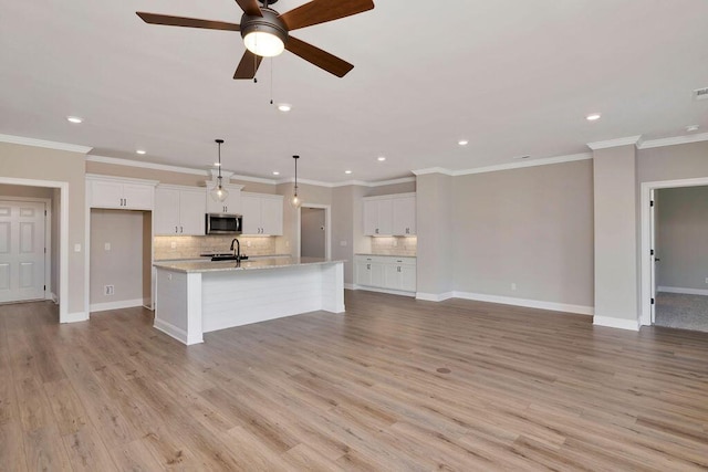 kitchen with an island with sink, sink, white cabinets, and light hardwood / wood-style floors