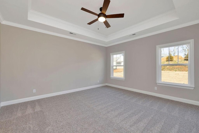 empty room with a raised ceiling, ornamental molding, carpet flooring, and ceiling fan