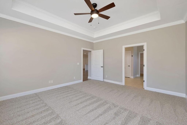 unfurnished bedroom with crown molding, light carpet, ceiling fan, and a tray ceiling