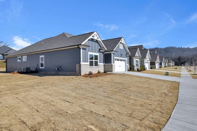 view of side of property with a garage, a yard, and central air condition unit