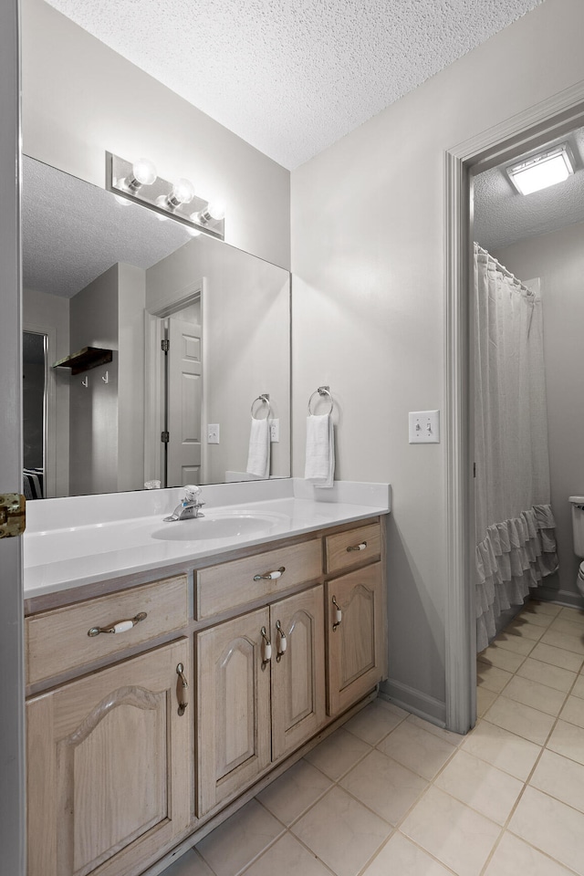 full bath featuring a textured ceiling, tile patterned flooring, and vanity