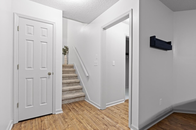 stairway with baseboards, a textured ceiling, and wood finished floors