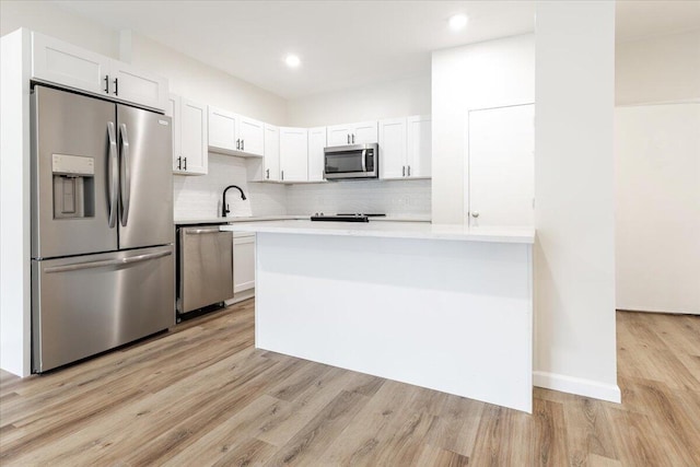 kitchen with stainless steel appliances, light wood-type flooring, white cabinetry, backsplash, and sink