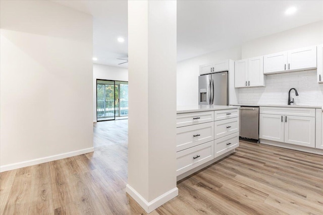 kitchen with stainless steel appliances, light hardwood / wood-style floors, white cabinetry, and backsplash